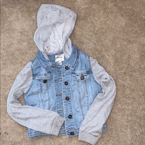 A blue jean jacket with grey sleeves.